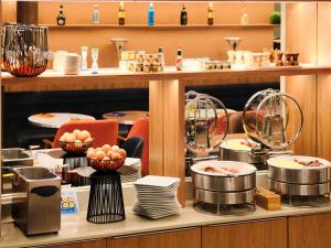 a restaurant with plates and dishes on a counter at Mercure Chartres Cathedrale in Chartres