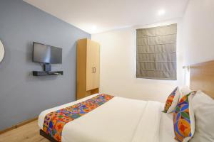 a bedroom with a bed and a tv on the wall at FabHotel Vivek in Muthiganj