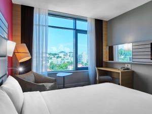 um quarto de hotel com uma cama e uma grande janela em Mercure Sochi Centre Hotel em Sochi