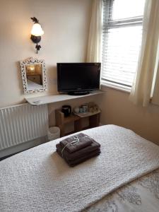 a bedroom with a bed and a television and a mirror at Heather Lea Guest Rooms in Blackpool