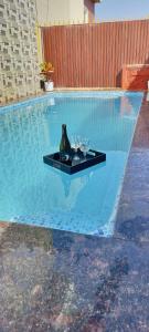 einen Tisch mit Weingläsern und eine Flasche im Pool in der Unterkunft Sunshine villa panchgani 5 bedrooms villa in Panchgani