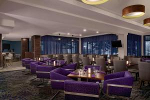 a restaurant with purple chairs and tables and windows at Hilton Garden Inn Calgary Airport in Calgary