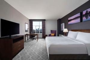 a hotel room with a bed and a flat screen tv at Hilton Garden Inn Calgary Airport in Calgary