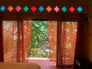 Schlafzimmer mit einem Bett und einem Fenster mit Vorhängen in der Unterkunft One World Bungalows in Ko Lanta
