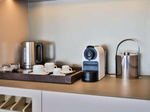 a kitchen counter with a coffee maker and coffee cups at Palladio Hotel Buenos Aires - MGallery in Buenos Aires