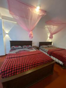 two beds in a room with red and black sheets at Blue Sky Guest House And Restaurant in Nallathaniya