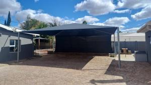 a large blue tent in a yard next to a building at Winemaker's Rest in Oudtshoorn
