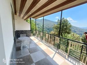 balcón con mesa y vistas a las montañas en Auroville Home stay, en Shimla