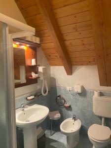 uma casa de banho com 2 lavatórios e um WC em Hotel Aplis em Ovaro
