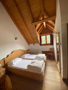 two beds in a room with wooden ceilings at Hotel Aplis in Ovaro