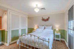 1 dormitorio con cama blanca y paredes verdes en Tanwarra Lodge, en Sofala
