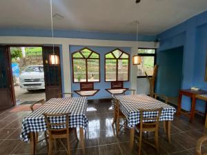 a dining room with two tables and chairs and windows at Blue Sky Guest House And Restaurant in Nallathaniya