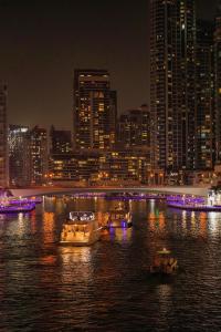 uno skyline della città con barche in acqua di notte di Happy ACADEMIA JBR a Dubai