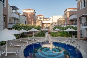 a courtyard with a pool and chairs and umbrellas at Caldera Bay in Plataniás