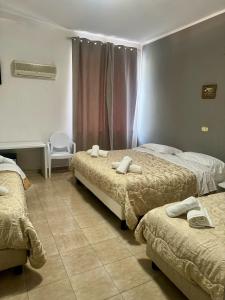 une chambre d'hôtel avec deux lits et une chaise dans l'établissement Hotel Il Santuario - Pompei, à Pompéi