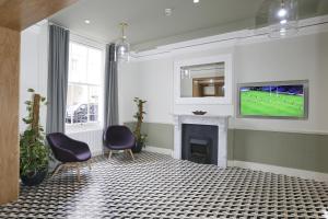 a living room with a tv and a fireplace at Prince William Hotel in London