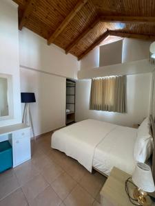 1 dormitorio con cama blanca y escritorio en Hotel Kolagji, en Himare