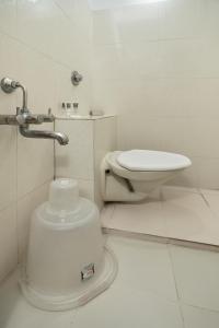 a white bathroom with a toilet and a sink at Aishwarya Mystic Apartotel in Bangalore