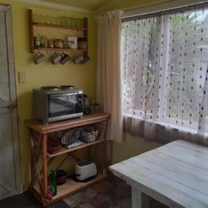 a kitchen with a microwave and a table and a window at Dream Weavers Farm Cabin in Karetu