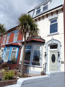 a white house with a palm tree in front of it at Heather Lea Guest Rooms in Blackpool