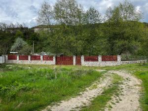 a dirt road in a field next to a fence at La Grădina in Mehadia