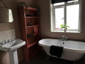 a bathroom with a tub and a sink and a window at The Snug in Fordingbridge