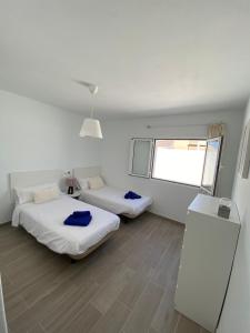 two beds in a white room with a window at Playa Honda primera línea in Playa Honda