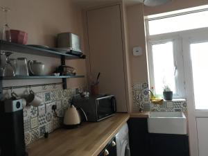 a small kitchen with a microwave and a sink at The Snug in Fordingbridge