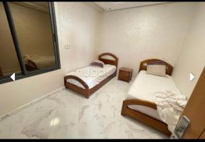 um pequeno quarto com 2 camas e um espelho em Sunny house em Tânger