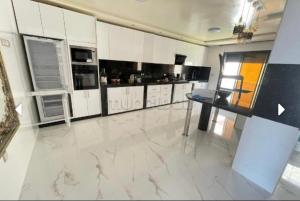 uma grande cozinha com armários brancos e piso em mármore em Sunny house em Tânger