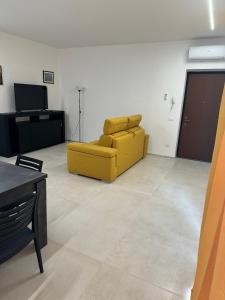 uma sala de estar com um sofá amarelo e uma televisão em Appartamento Umberto em Piacenza