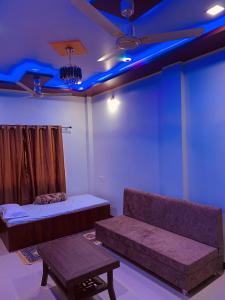 a room with a couch and a table and blue lights at Manjushree Guest House in Ujjain