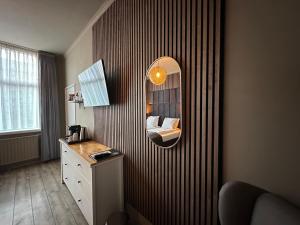 a room with a mirror on a wall with a dresser at Hotel Buren in West-Terschelling