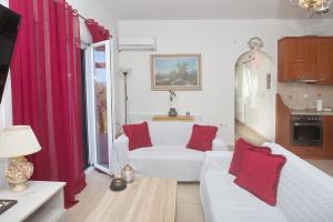 a living room with a white couch and red pillows at Eleni's House by Corfuescapes in Corfu