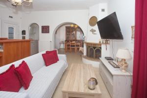 a living room with a white couch and a tv at Eleni's House by Corfuescapes in Corfu