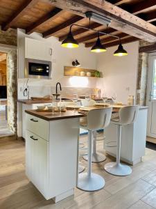 a kitchen with white cabinets and a island with bar stools at Aux petites portes du Morvan in Montlay-en-Auxois