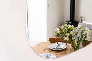 a dining room table with a vase of flowers at Meadow View Barn, Rural St Ives, Cornwall. Brand New 2 Bedroom Idyllic Contemporary Cottage With Log Burner. in Nancledra