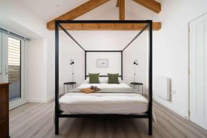 a bedroom with a black canopy bed with green pillows at Meadow View Barn, Rural St Ives, Cornwall. Brand New 2 Bedroom Idyllic Contemporary Cottage With Log Burner. in Nancledra