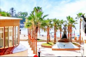 kobieta spacerująca po plaży z palmami w obiekcie Apartamento Puerto Sol y Mar w mieście Fuengirola