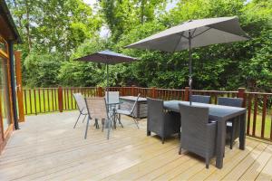 una terrazza con tavolo, sedie e ombrelloni di Conkers Retreat at Finlake Resort & Spa, Devon a Chudleigh