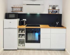una cocina con armarios blancos y horno negro en Dream Apartments 3B KLIMATYZACJA, en Oświęcim
