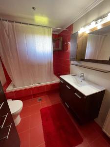 Baño rojo con lavabo y aseo en Villa Manolia, en Krikellos