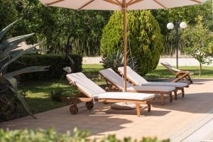 4 Liegestühle und ein Sonnenschirm auf einer Terrasse in der Unterkunft Pelion's Finest Estate in Káto Lekhónia