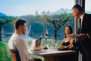 un grupo de personas sentadas en una mesa con comida y vino en Parc Hotel Du Lac en Levico Terme