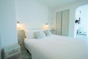 a white bedroom with a white bed with two pillows at Villa Ravino Secret Retreat in Ischia