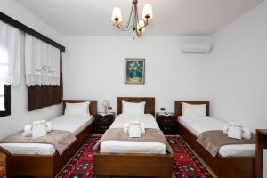 Habitación con 3 camas y lámpara de araña. en Villa ELMAR, en Berat