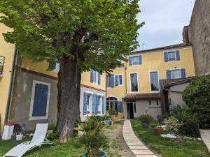 エール・シュル・ラドゥールにある"Le Jardin sur l'Eau "chambres d'hôtes et appartement tout confortの黄色い建物の前の木