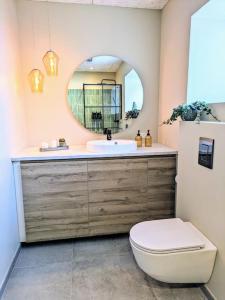 een badkamer met een wastafel, een toilet en een spiegel bij Cozy apartment in Runavík in Saltangará