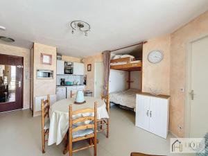 Habitación con mesa y dormitorio con litera. en Appart Vue Mer 3e Étage, Idéal 2-4 Pers, Confort, en Bray-Dunes