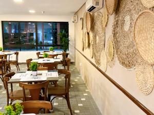 ein Restaurant mit Tischen und Stühlen in einem Zimmer in der Unterkunft Flat Luxury Chelsea frente ao Dona Lindu in Recife